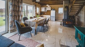A spacious living area with a dining table, chairs, a sofa, and a fireplace. - Large Holiday Home, Jacuzzi, Sauna, Salt Cave (Lipusz)