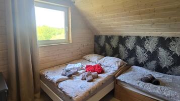 A bedroom with two beds, a window, and a patterned wall.