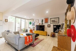 Un salon avec un canapé, un téléviseur et des œuvres d’art accrochées au mur.