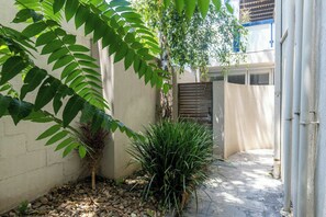 A narrow outdoor corridor with a concrete wall, a metal gate, and a potted plant. - Spacious 1BDR in St Kilda Near Tram and Beach (St Kilda)