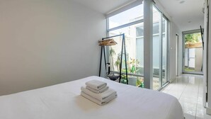 Een moderne hotelkamer met een groot bed, een hangstoel en uitzicht op het landschap.