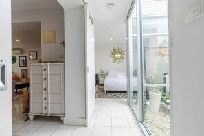 A hotel room with a bed, a nightstand, a dresser, and a large window offering a view of the outdoors. - Spacious 1BDR in St Kilda Near Tram and Beach (St Kilda)