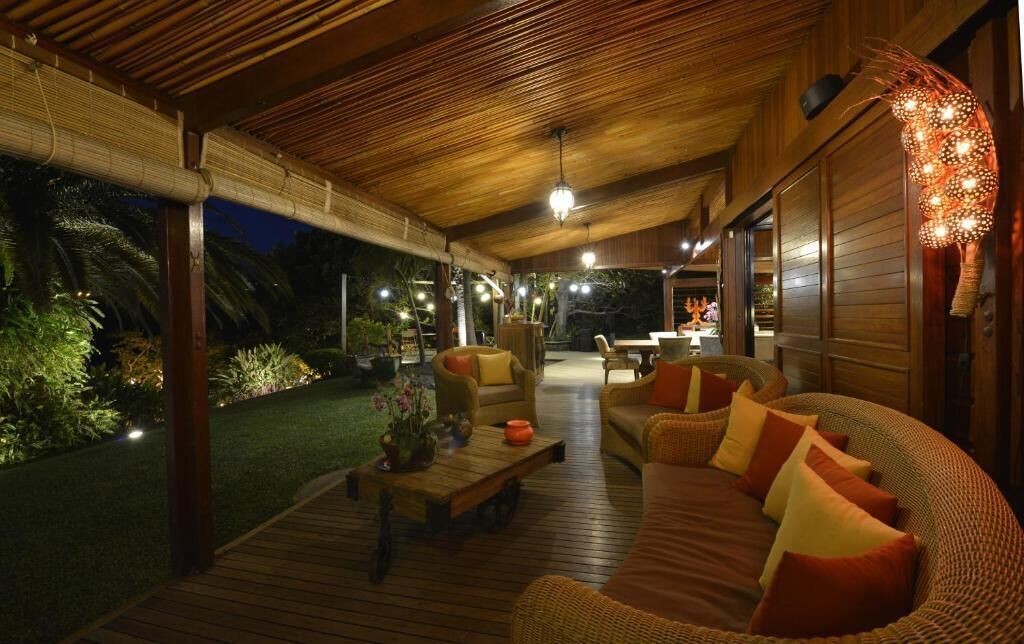 An outdoor seating area with a wooden deck, wicker furniture, and ambient lighting.