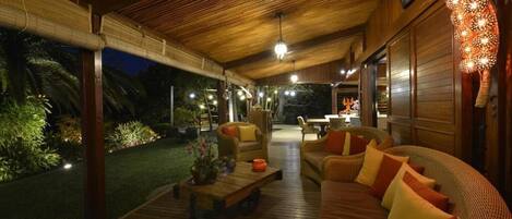 An outdoor seating area with a wooden deck, wicker furniture, and ambient lighting.