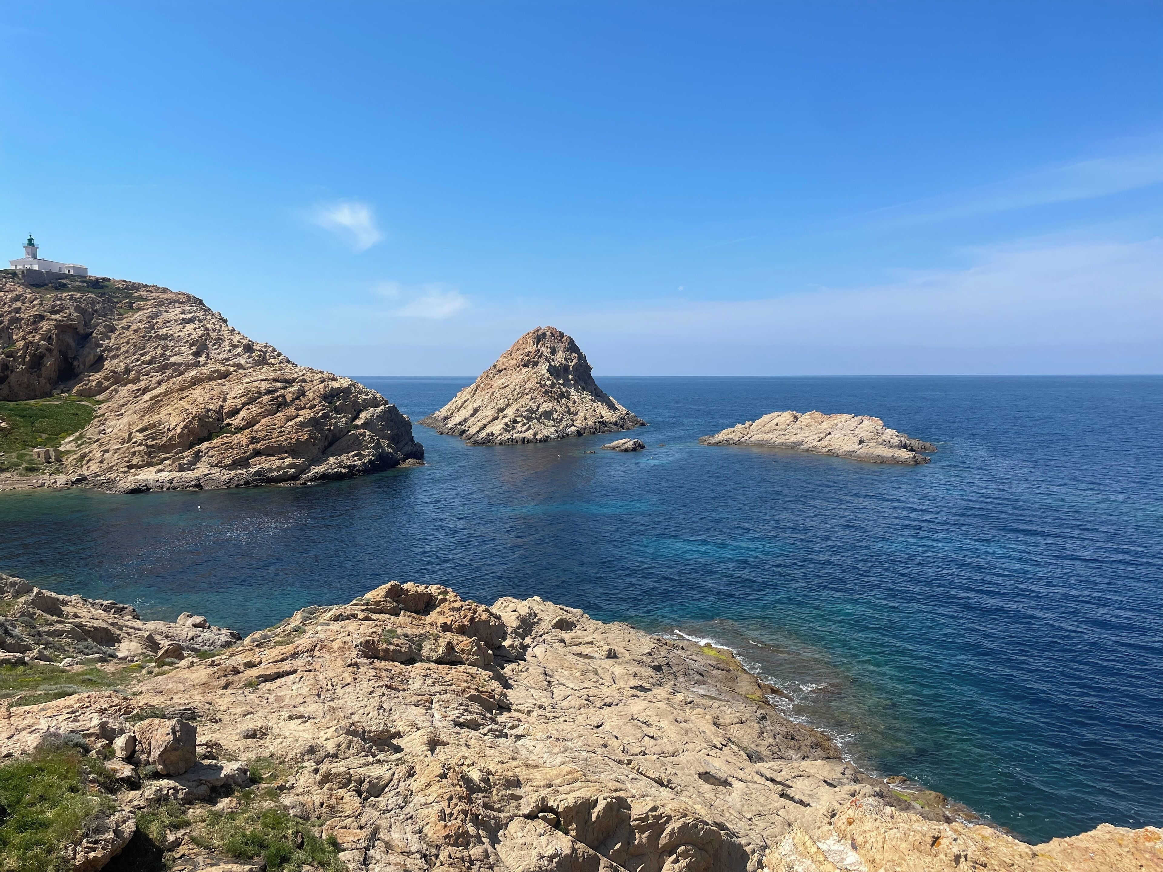 A coastal landscape with rocky terrain and a lighthouse on a cliff.