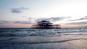 A pier structure extending into the sea with waves gently lapping at its base. - Steps from Beach & Lanes | Stylish Brighton (Brighton and Hove)