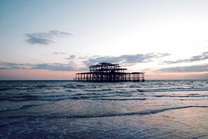 A pier structure extending into the sea with waves gently lapping at its base. - Steps from Beach & Lanes | Stylish Brighton (Brighton and Hove)