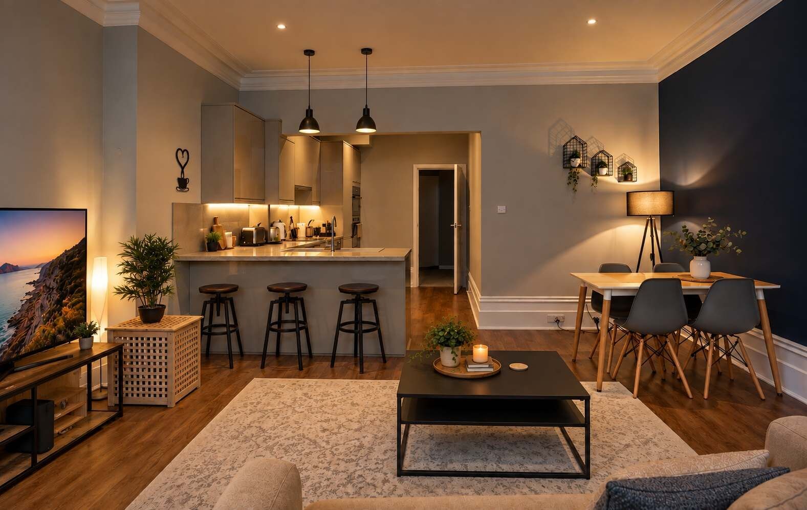 A modern living room with a kitchen area, bar stools, a dining table, and a TV.