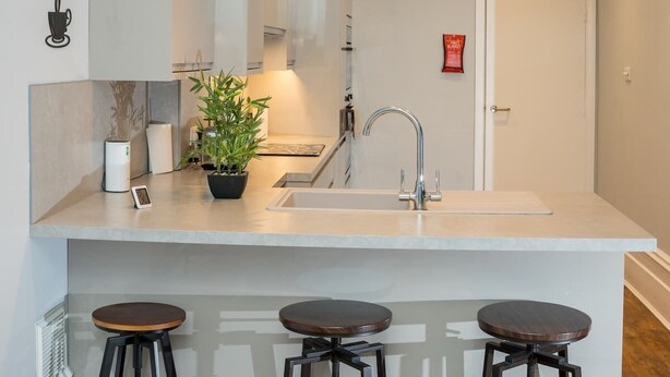 A modern kitchen with a central island, bar stools, pendant lighting, and a built-in sink. - Steps from Beach & Lanes | Stylish Brighton (Brighton and Hove)