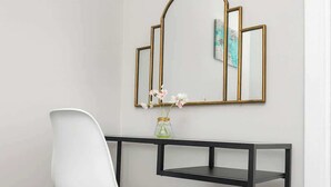A white chair with wooden legs, a black metal desk, and a gold-framed mirror on the wall. - Steps from Beach & Lanes | Stylish Brighton (Brighton and Hove)