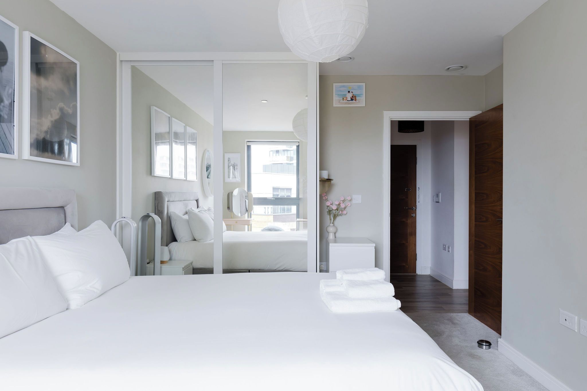 A modern bedroom with a large bed, a walk-in closet, and a bathroom with a mirror and sink.