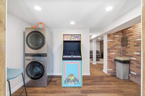 A laundry area with stacked washing machines and a retro arcade machine.