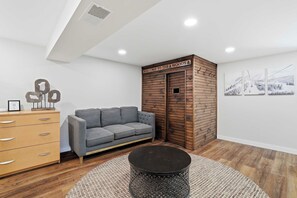 Un salon moderne avec un canapé gris, un meuble en bois et un panneau décoratif fixé au mur.