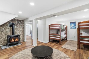 A modern living room with a stone fireplace, bunk beds, and a round coffee table.