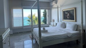 Un lit à baldaquin avec vue sur la mer, un tableau au mur et un radiateur.