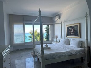 A four-poster bed with a view of the sea, a painting on the wall, and a radiator. - Cliff Apartment with sea view in Sidi Bou Saïd (Site archéologique de Carthage)
