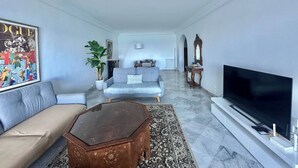 Un salon moderne avec un canapé, une table basse, un téléviseur et un grand tableau accroché au mur.
