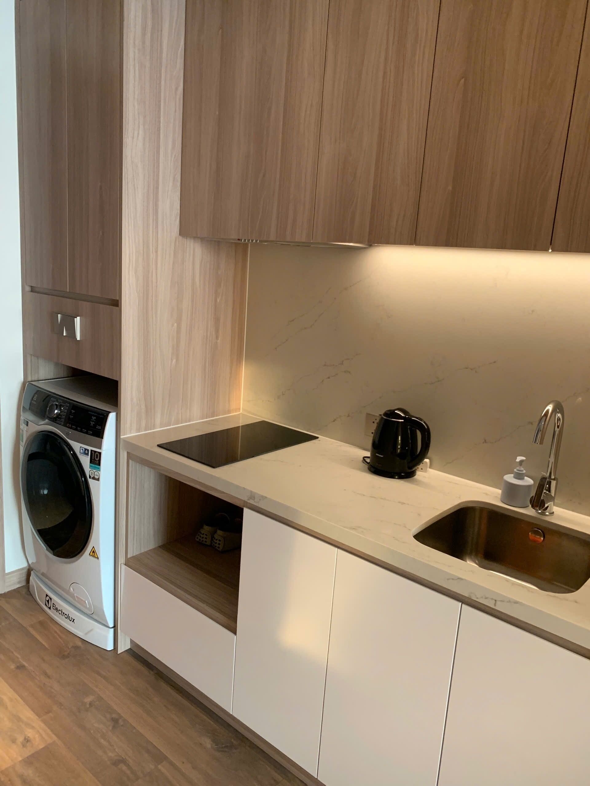 A compact kitchen with a built-in washing machine, a coffee maker, and a sink.