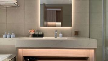 Un baño moderno con un espejo grande, un lavabo de mármol y un mueble de tocador de madera.