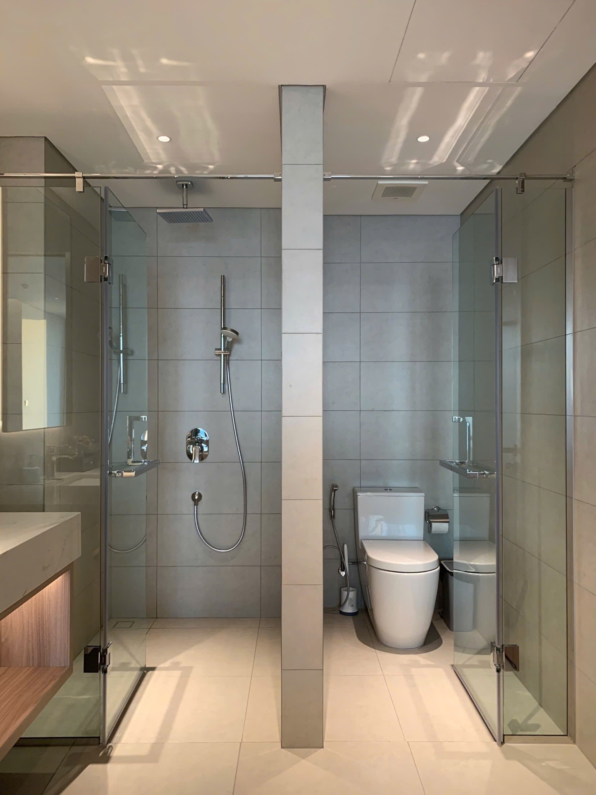 A modern bathroom with a glass shower enclosure, a toilet, and a sink.