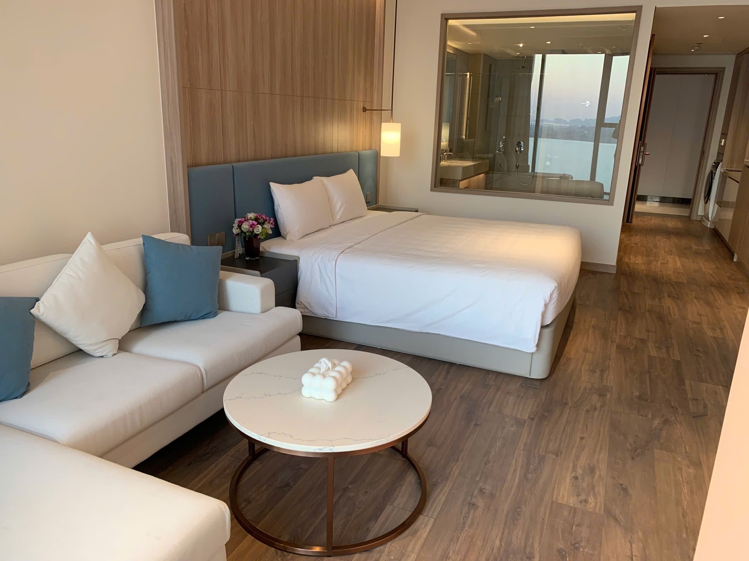 Ein modernes Hotelzimmer mit einem Bett, einer Couch und einem runden Couchtisch.