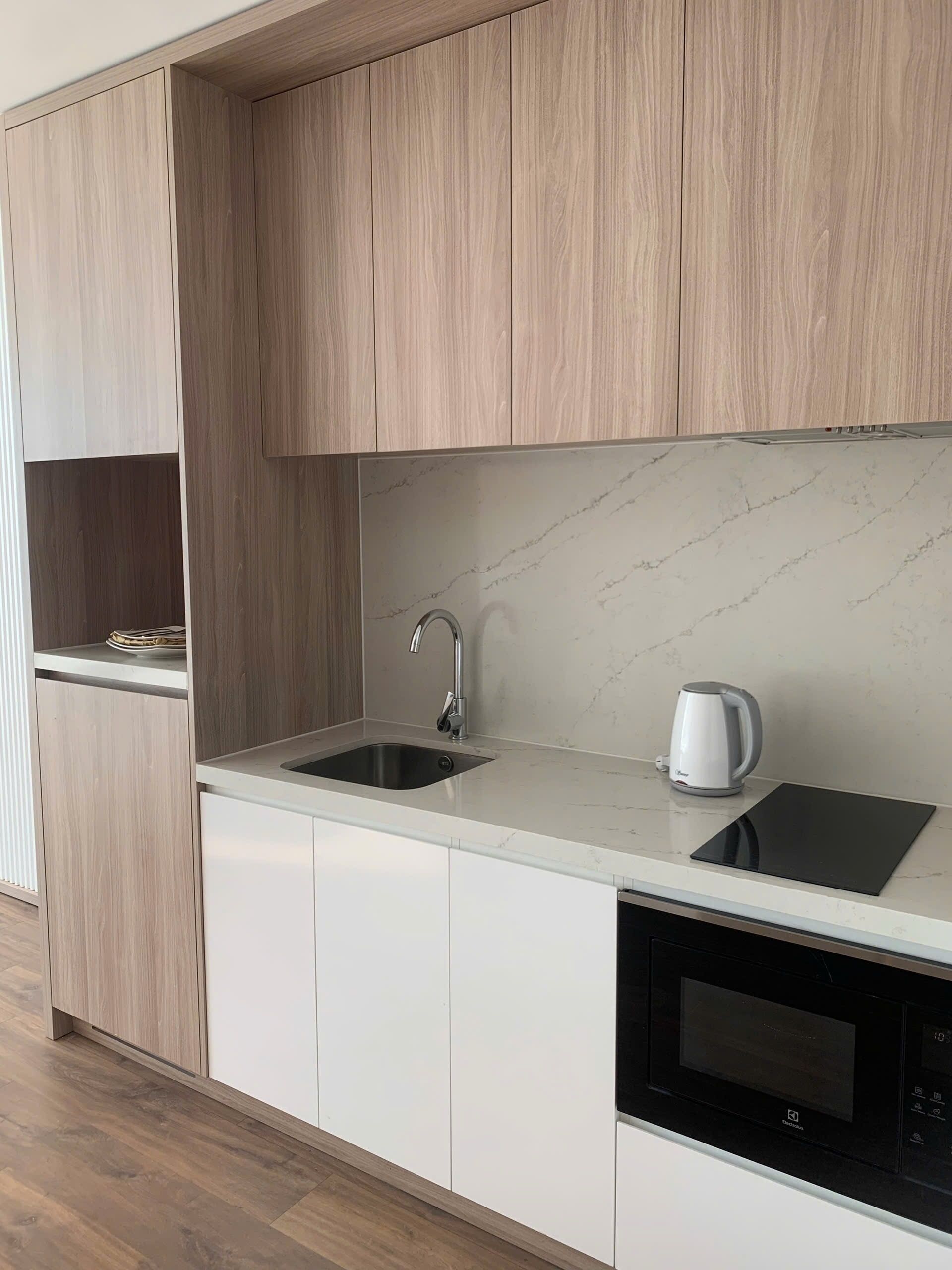 A modern kitchen with a marble countertop, stainless steel sink, and a built-in microwave.