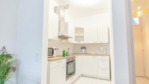 Una cucina moderna con mobili bianchi, un forno a microonde, un lavello e un piano cottura.