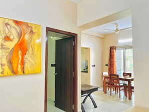 A modern dining area with a wooden table and chairs, a ceiling fan, and a view through a glass door. - GOOD STAY T.NAGAR, NEAR KAUARY, Apollo hospital & American Embassy (Chennai)