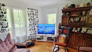 Ein gemütliches Wohnzimmer mit Fernseher, Schaukelstuhl und Bücherregal.