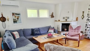 Ein gemütliches Wohnzimmer mit einem blauen Ecksofa, einem Holztisch und einem pinkfarbenen Sessel.