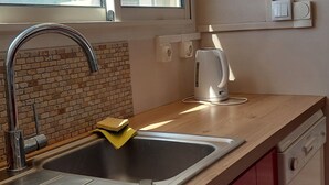 Een keuken met een roestvrijstalen spoelbak, een waterkoker en een raam met uitzicht op bergen.