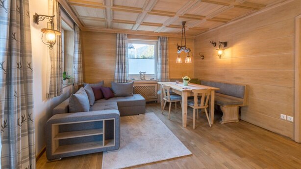 Ein gemütliches Wohnzimmer mit einer Eckcouch, einem Esstisch und einer Bank.