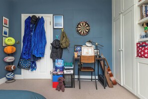 Une pièce avec un jeu de fléchettes, des ballons de sport, une guitare et une chaise.