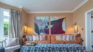 Une chambre à coucher avec un grand lit, une chaise longue et deux tableaux accrochés au mur.