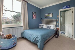 A bedroom with a bed, a window with curtains, a wall-mounted picture, and a door. - Beautiful 5BDR 3Bath Home in Barnes (Greater London)