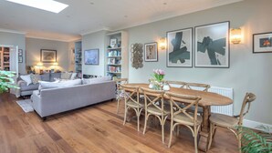 Un salon comprenant un canapé, une table à manger avec des chaises, une bibliothèque et des œuvres d’art murales.