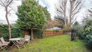 Un jardin avec une table et des chaises en bois, un grand arbre et une clôture en bois.