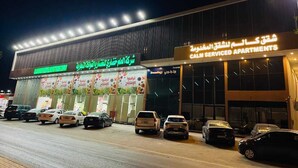 A building with multiple car service bays and a sign for 'CAM Serviced Apartments'.