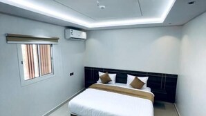 Un dormitorio moderno con una cama grande, un aplique de techo y una ventana con persianas.