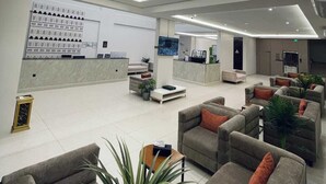 A modern lobby with a reception desk, seating area, and a large illuminated ceiling.