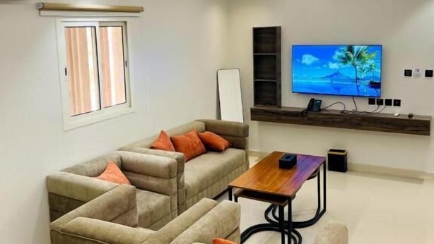 Una sala de estar moderna con un sofá modular, una mesa de centro y un televisor de pantalla plana montado en la pared.