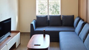 Ein modernes Wohnzimmer mit Ecksofa, Flachbildfernseher, Couchtisch und Deckenventilator.