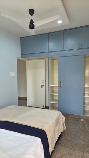 A bedroom with a bed, a wardrobe, and a ceiling fan. - Cozy 2-bedroom apartment in amazing Bengaluru neighborhood (Bengaluru)