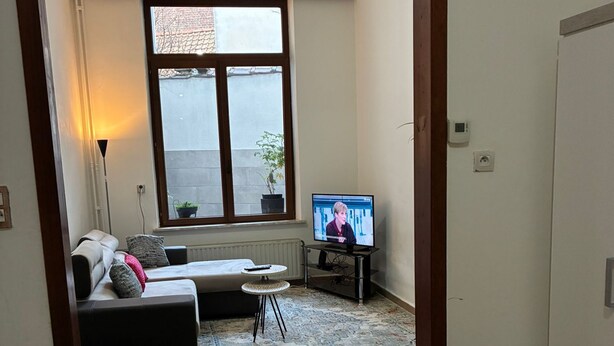Ein Wohnzimmer mit einer Couch, einem kleinen runden Tisch und einem Fernseher.