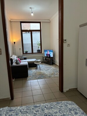 A living room with a sofa, a small round table, and a television. - Beautiful apartment (Molenbeek bruxelles)