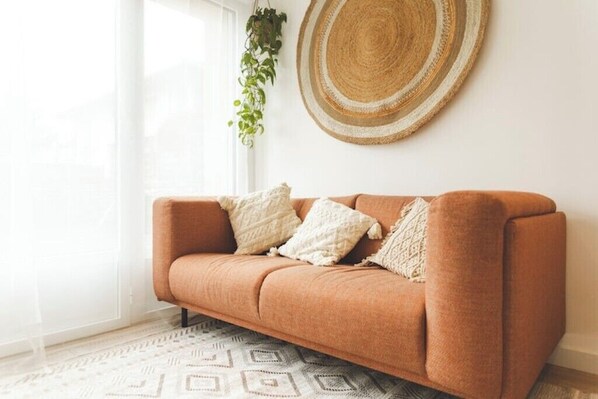 Une pièce chaleureuse avec un canapé marron, une tapisserie murale tissée et un tapis à motifs.