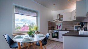 Una cucina moderna con zona pranzo, caratterizzata da un'ampia finestra, pavimento in legno e una macchina da caffè.