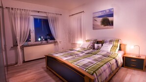 Una camera da letto con un letto, un comodino e una finestra con tende.