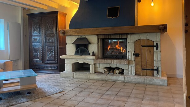 Una habitación con chimenea de piedra, puerta de madera y una mesa de vidrio.