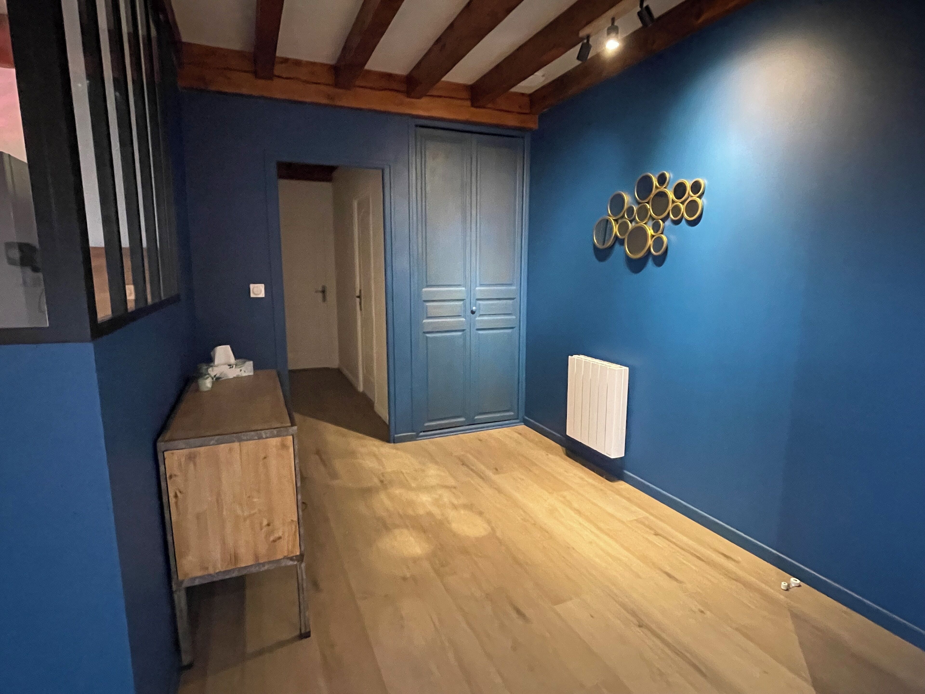 Una habitación con paredes azules, un armario de madera, una puerta y un radiador.